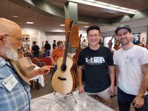 Bob Nance visits the table of Jeremy Houle and Alexander Neville, students representing Lutherie-Guitare Bruand. (D. Olsen)
