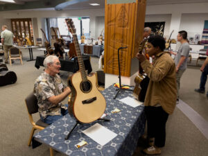 Neil Peterson chats with Mariah Roberson as she plays one of his guitars. (McElrath)