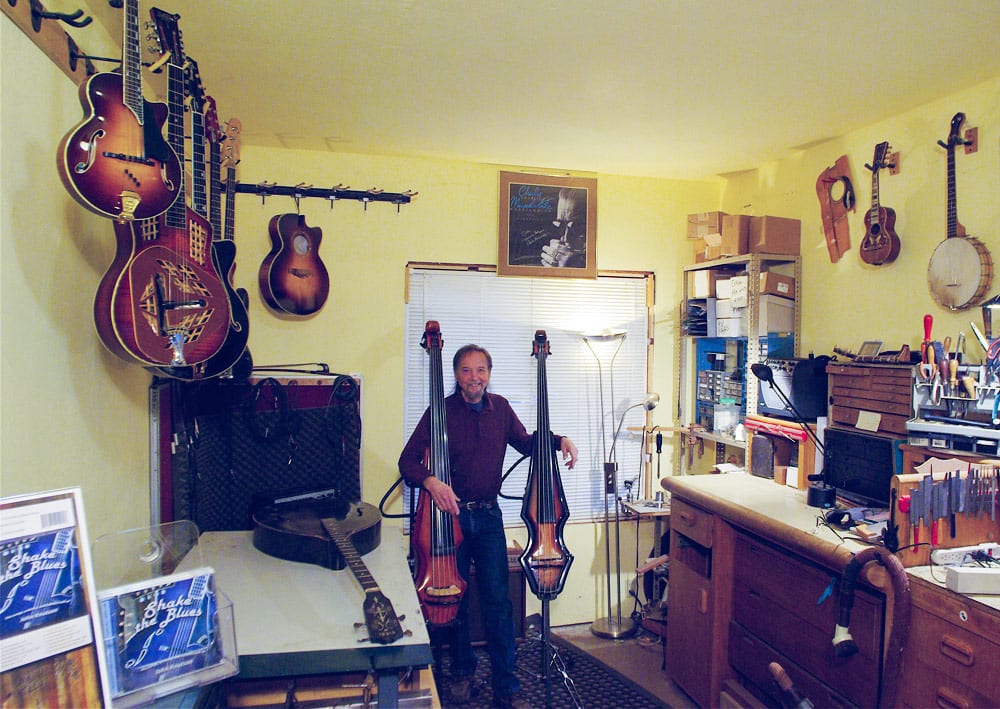 John hanging in his shop with two of his Messenger electric bases. The instrument lying on the table at left is a Raffaele Tieri bass mandolin, made in New York, circa 1930. He restored it for David Grisman.