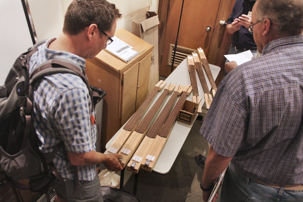 At his 2014 GAL Convention workshop, David King presented a matched set of dummy bass necks in which he had mounted different types of truss rods. Audience members check them out (Image 1 of 2).