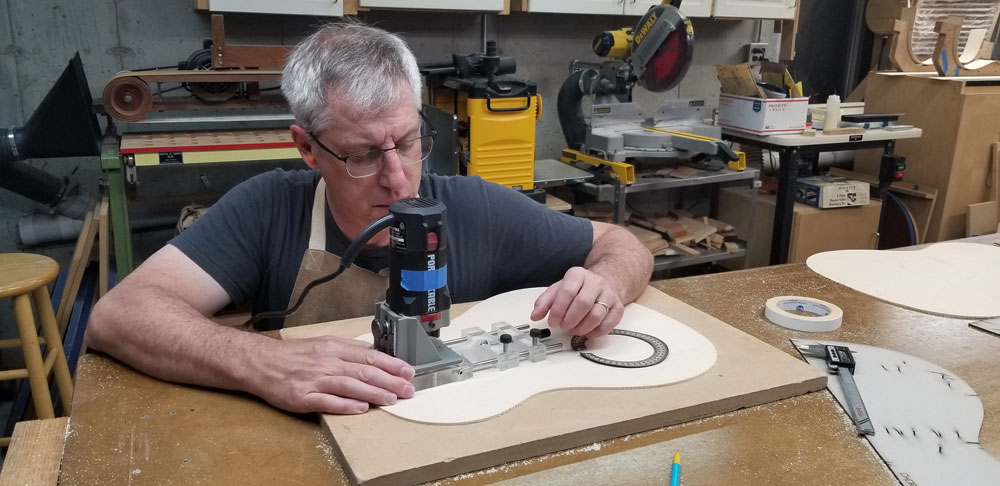 This is me using a trim router to cut the recess for the rosette that Paco supplied.  The rosette is under my left hand (which might not be the best place for it).