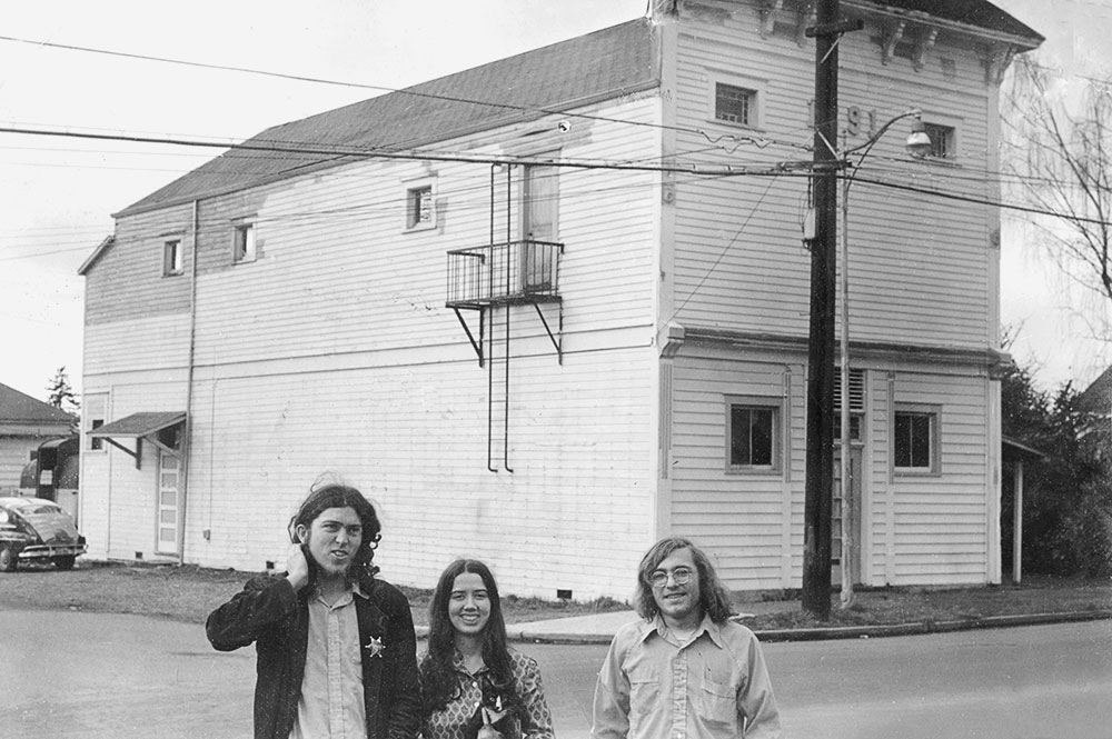 1973: Newlyweds Tim and Deb Olsen pose with Tim’s guitar-making partner Bob Petrulis in front of the affectionately named “Vetus Pigmentum” (loosely translated, “Old Paint”), the original and current GALHQ. Bob was the newsletter’s publisher in our early years, but had the good sense to follow a career path in higher education. He has remained a friend to the Guild all these decades and currently serves on our Board of Directors.